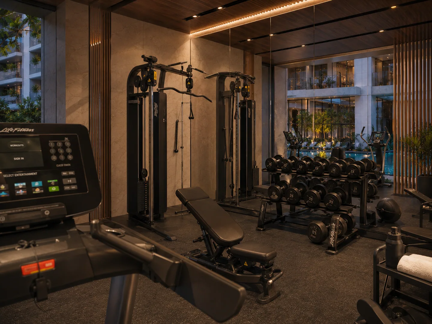 Same gym, different section: cable machine and free-weight rack in the foreground, pool visible through glass at rear.
